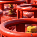 LPG cylinders at port with cargo ships highlighting stable supply via Strait of Hormuz